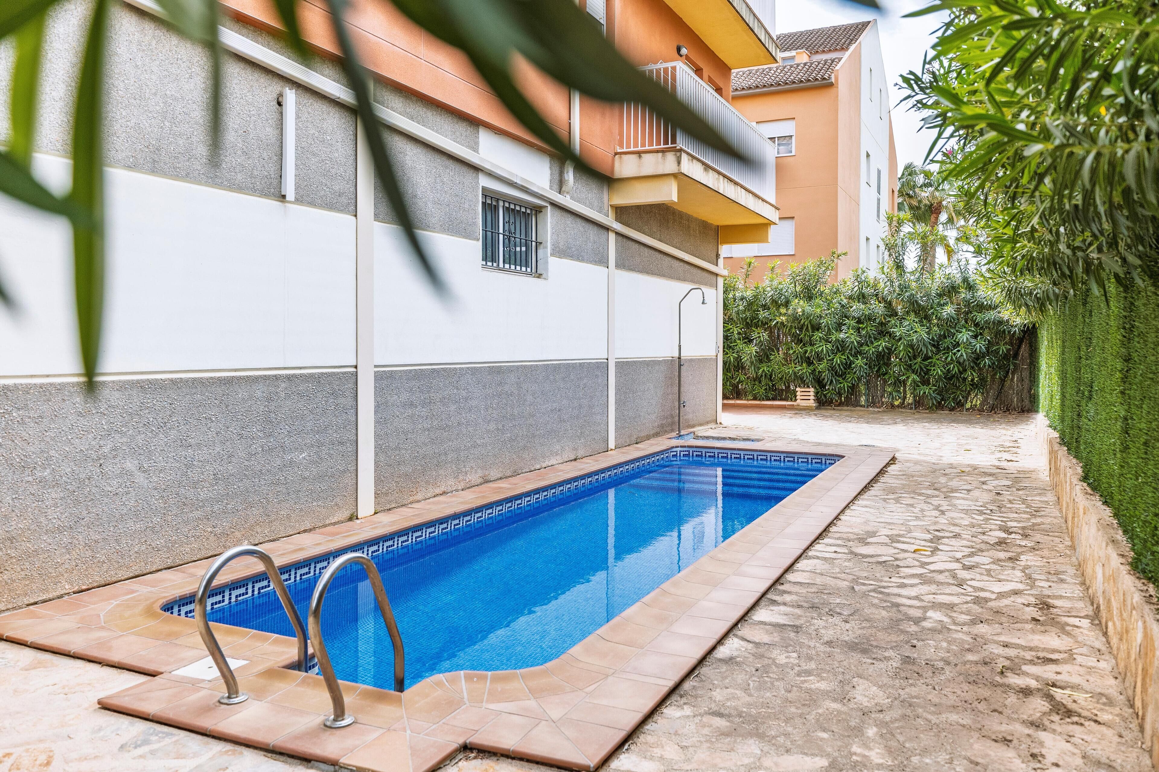 A swimming pool with a tiled edge, surrounded by a stone patio.