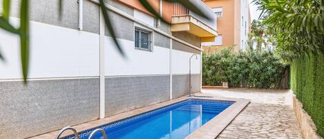 A swimming pool with a tiled edge, surrounded by a stone patio.