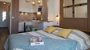 Ein modernes Schlafzimmer mit einem großen Bett, Nachttischen und einer kleinen Küchenzeile.