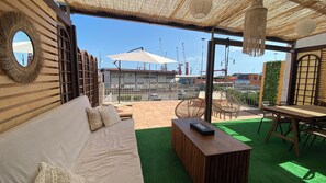 A rooftop terrace with a wooden sofa, hanging chairs, and a table. - Down at the harbor (Salerno)