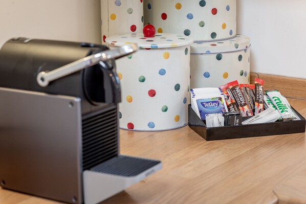 A coffee machine, two polka-dotted containers, and a tray with coffee pods and a Nespresso machine.