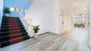 Een modern hotelinterieur met een trap, houten vloeren en een potplant.