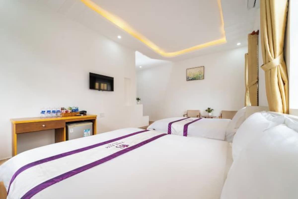 A hotel room with a bed, bedside tables, a desk, and a chair.