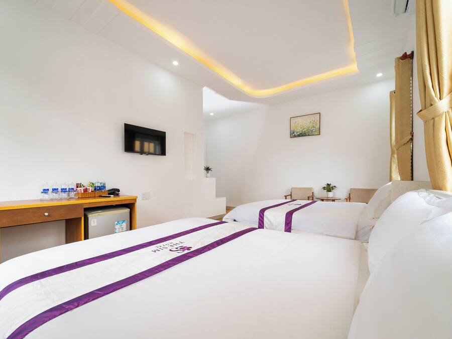 Habitación de hotel con cama, escritorio, un refrigerador pequeño y televisión.