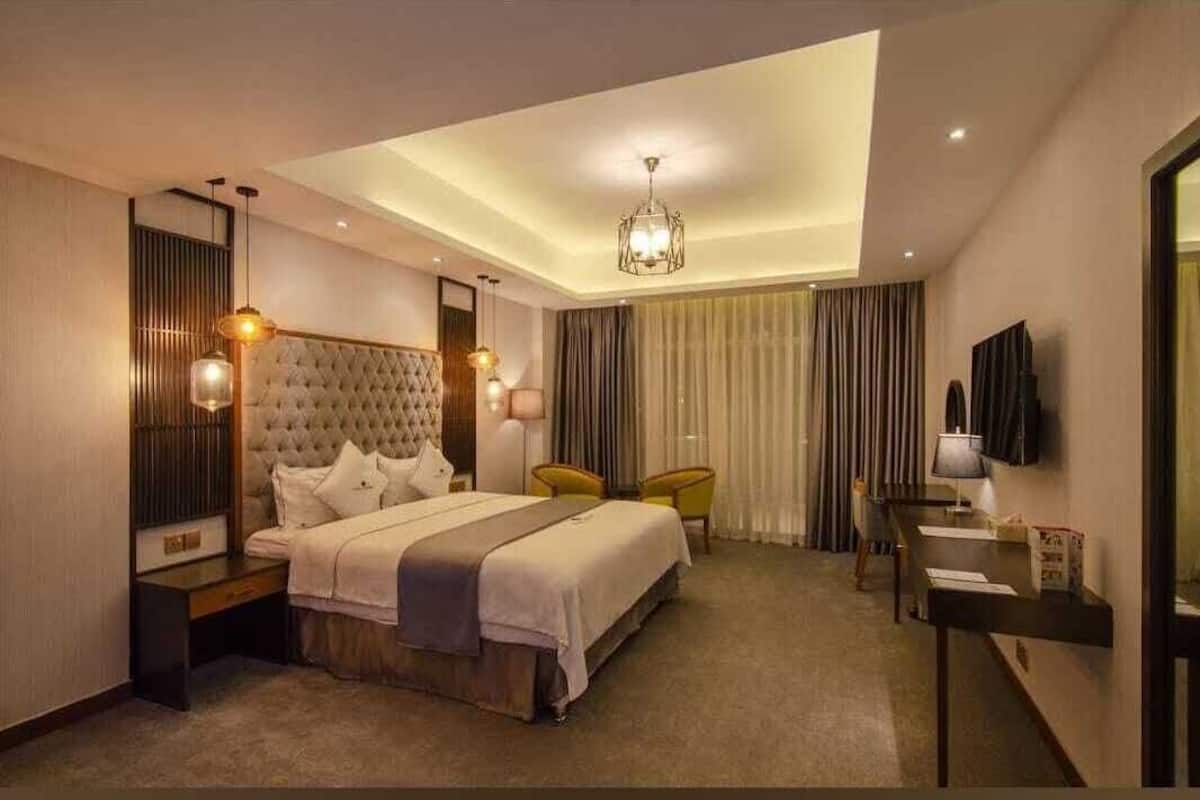 A modern hotel room with a large bed, a desk, and a television.