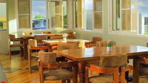 A dining area with wooden tables and chairs, large windows, and a view of the outdoors. - country sights Hotel Bulisa (Bulisa)
