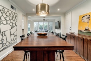A spacious dining area with a large wooden table, black chairs, and a central bowl.