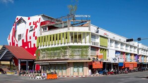 A midtown hotel with a distinctive red and white facade, multiple balconies, and a variety of shops on the ground floor.