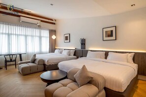 A hotel room with two beds, a sofa, a small table, and a desk.