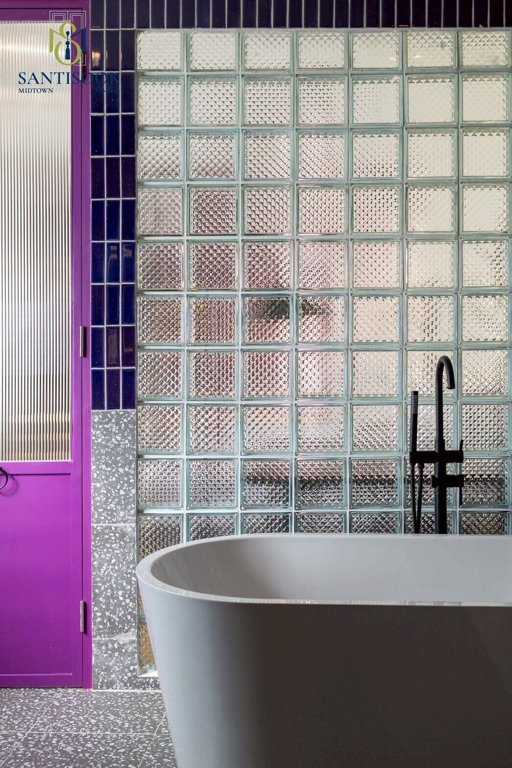 A bathroom with a white bathtub, a purple door, and a tiled wall with a grid pattern.