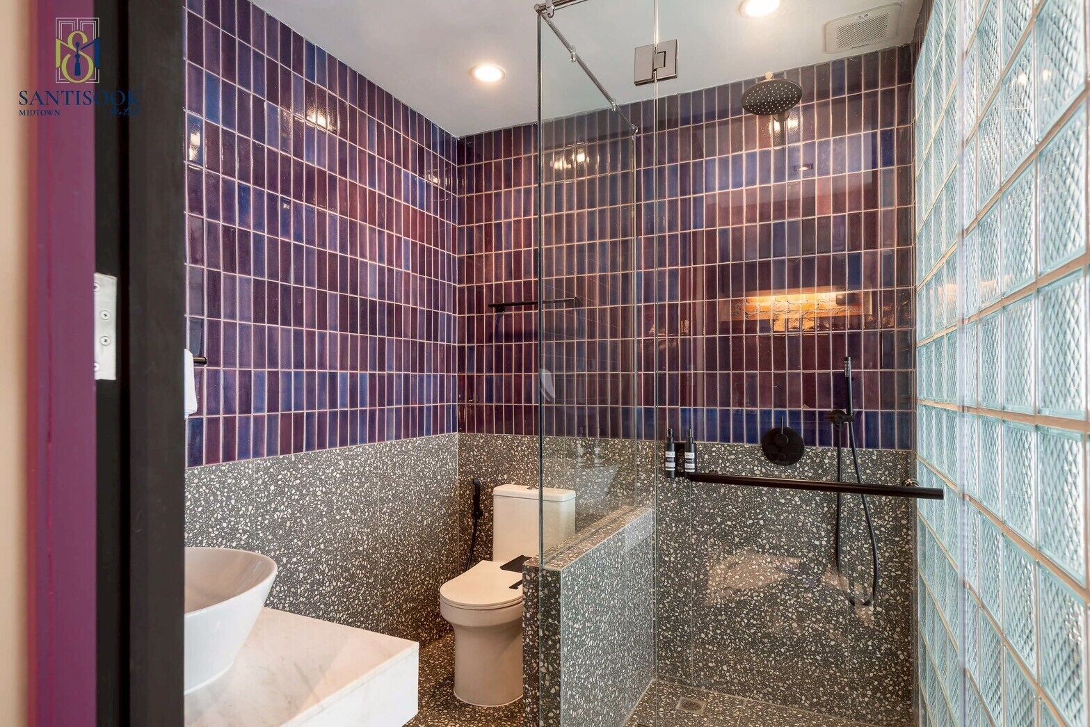 Un baño con cabina de ducha de vidrio, inodoro blanco y lavamanos de mármol.