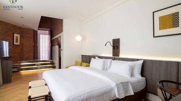 A modern hotel room with a large bed, a TV, a staircase, and a wall-mounted light fixture.