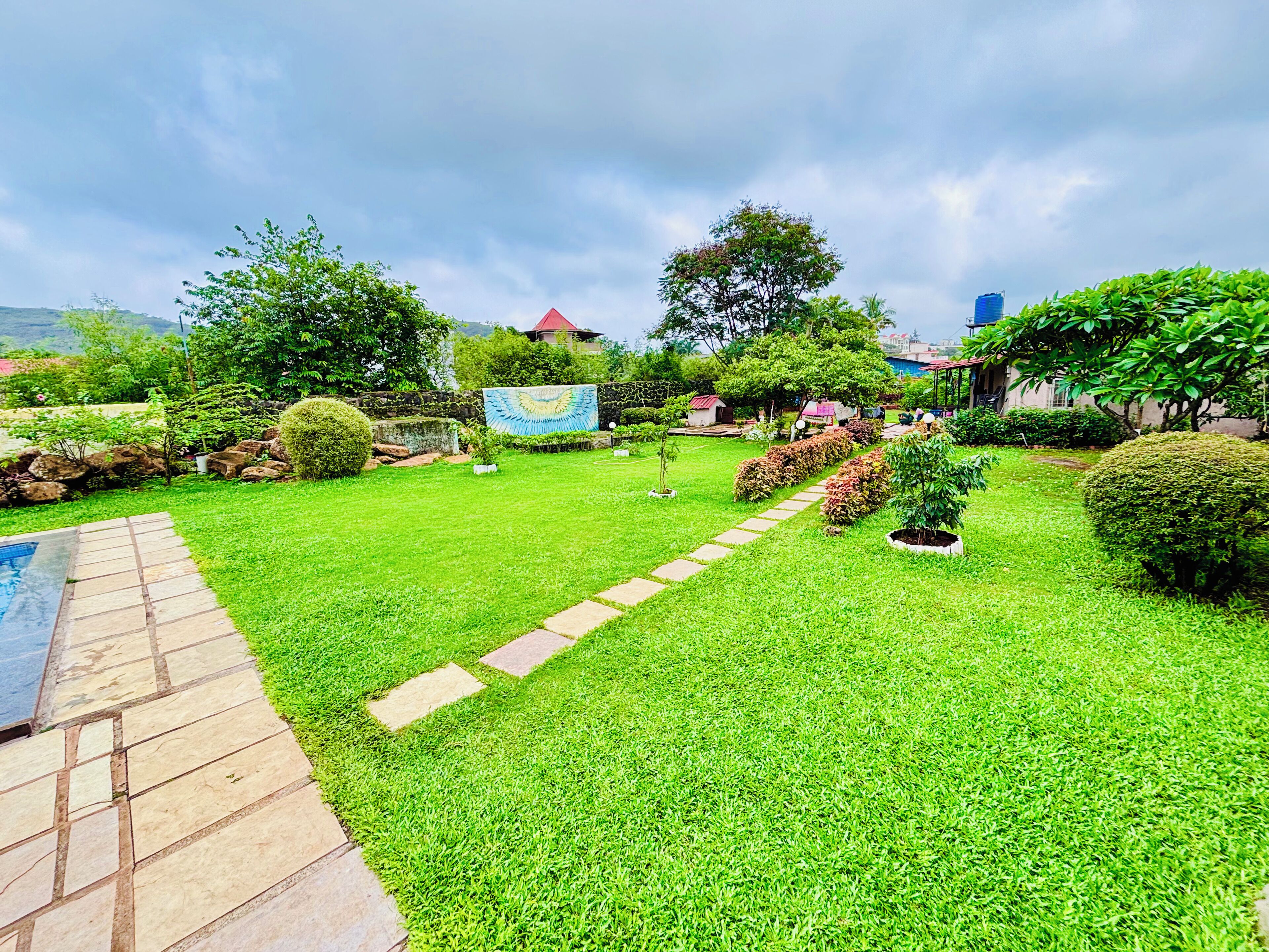 Ein gepflegter Garten mit einem Kiesweg, ordentlich geschnittenen Hecken und verschiedenen Bäumen und Sträuchern.
