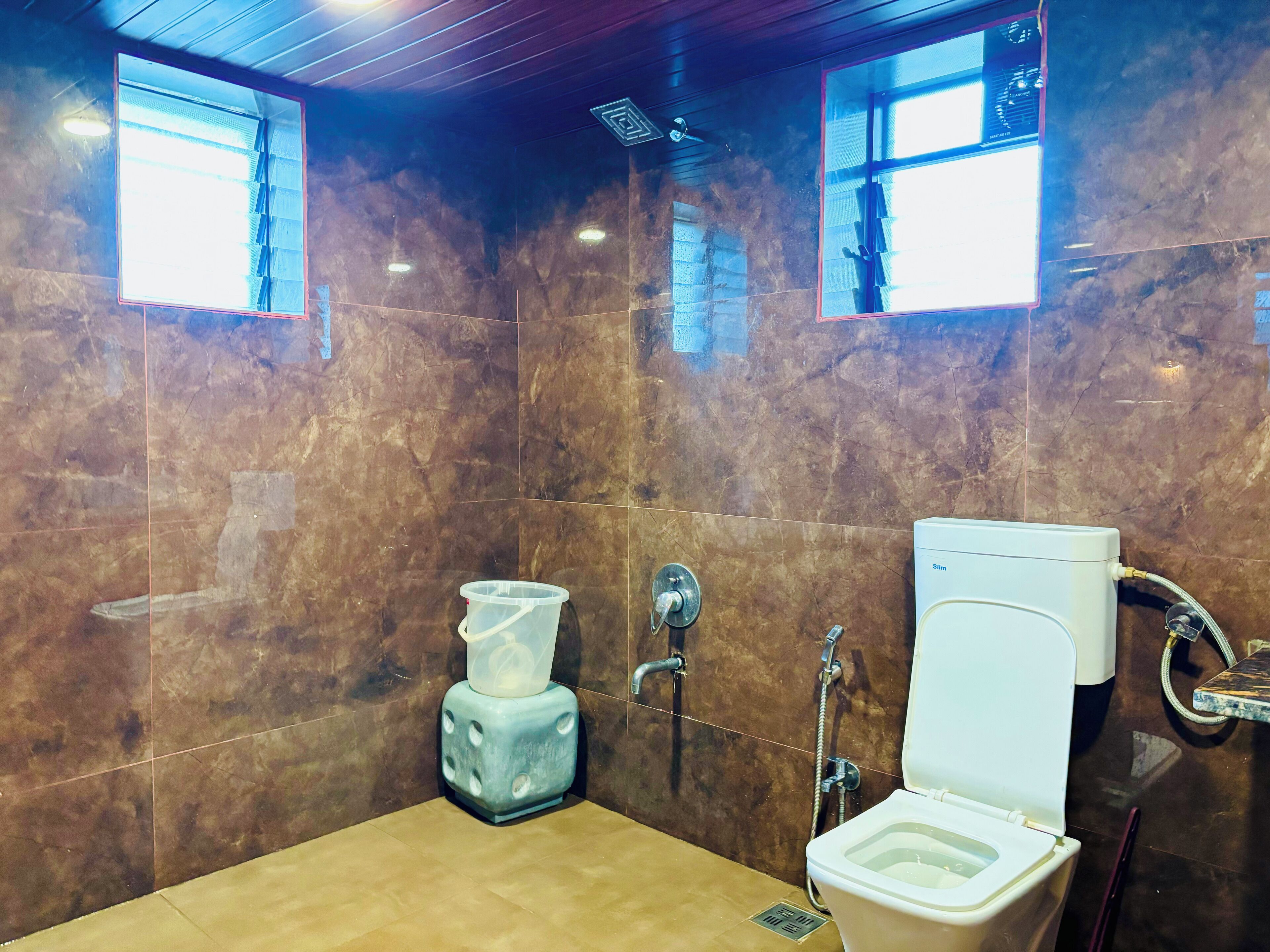 A bathroom with a marble wall, a toilet, a bidet, and a shower.