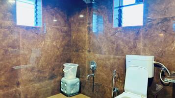 A bathroom with a marble wall, a toilet, a bidet, and a shower.