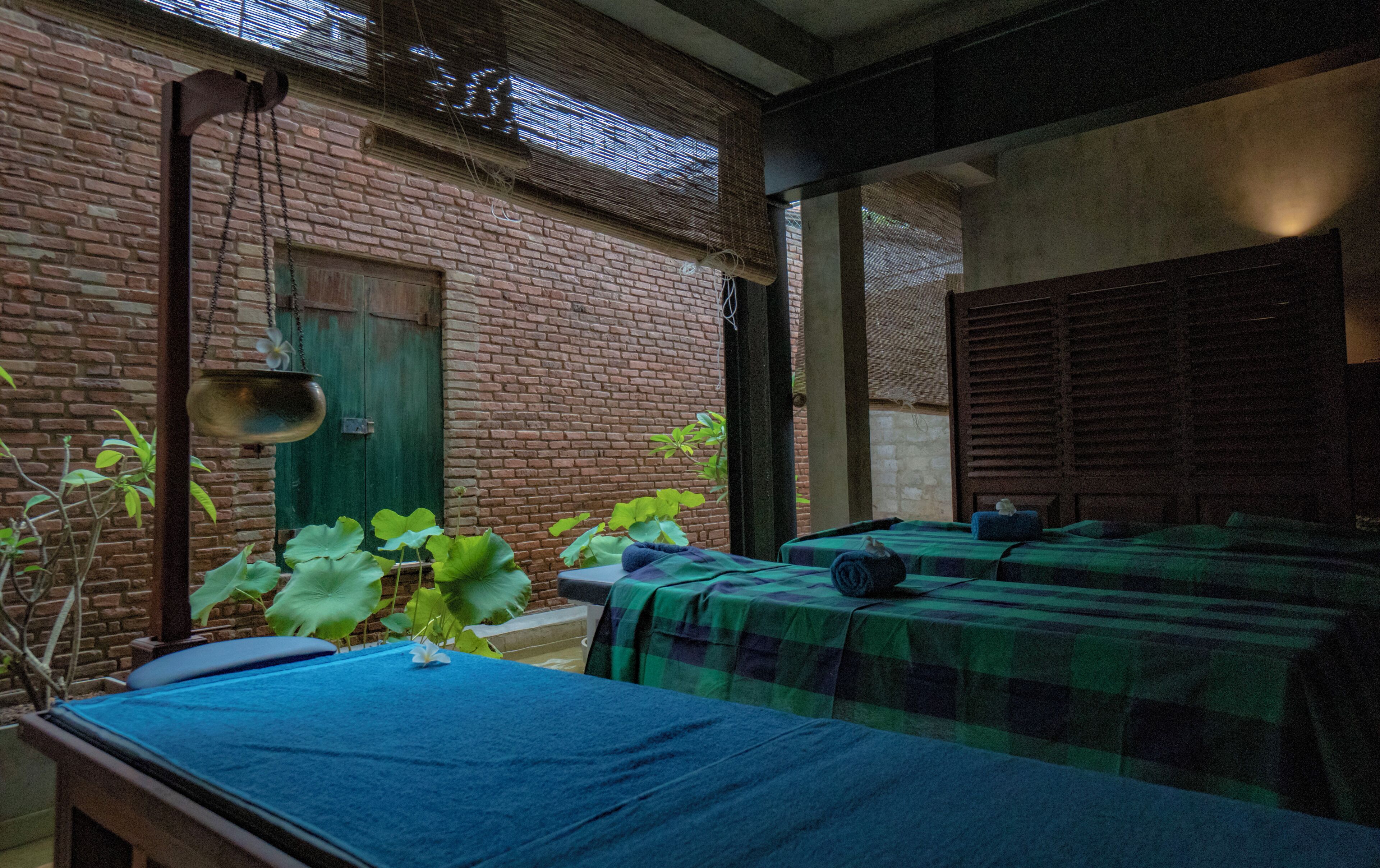 A room with two beds, a green door, and a brick wall.