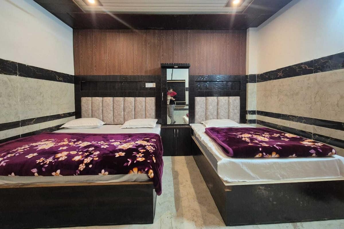 Ein Hotelzimmer mit zwei Betten, jeweils mit floralem Überwurf, einem Holzkopfteil und einem Spiegel an der Wand.