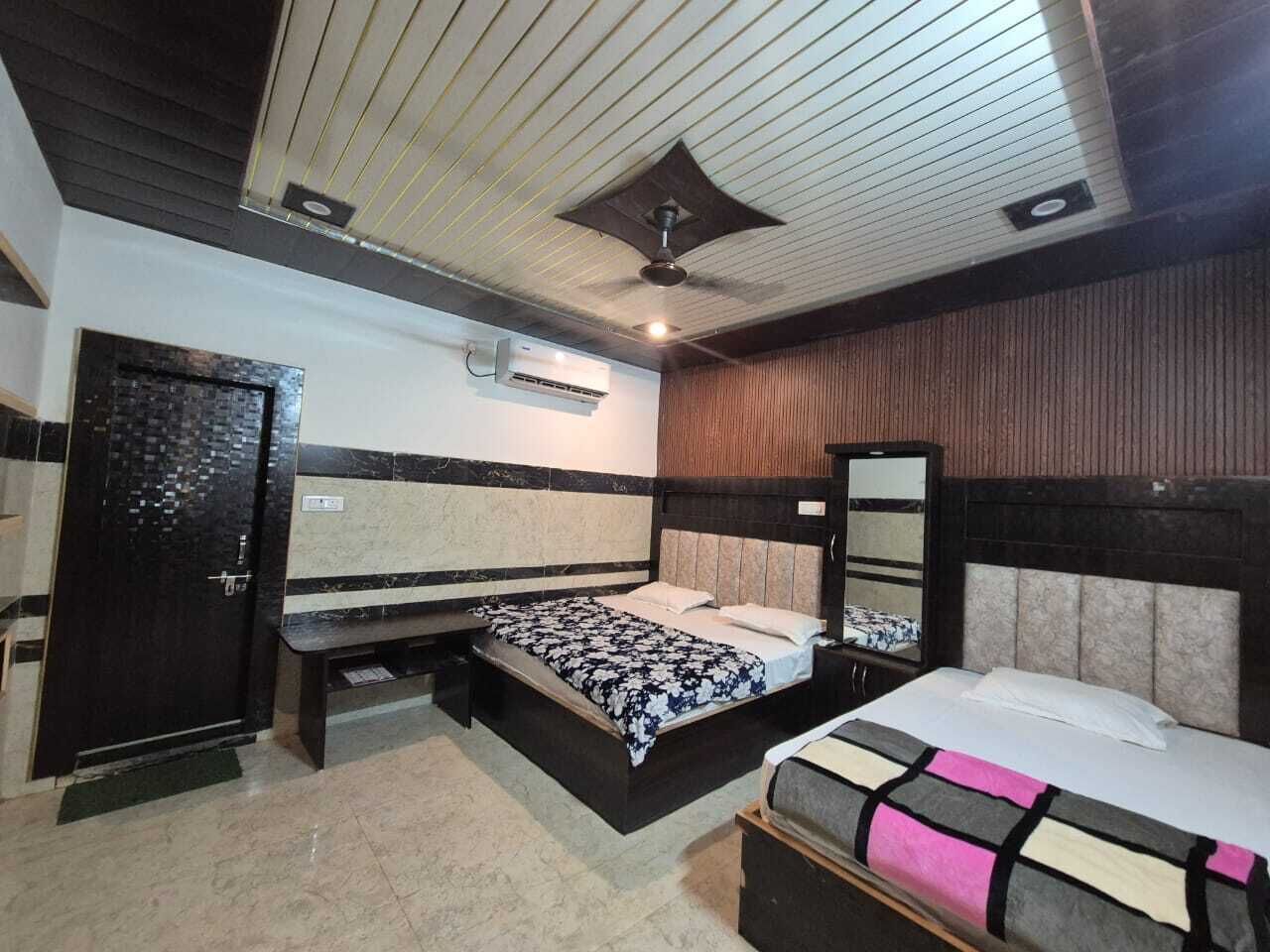 A bedroom with two beds, a wardrobe, a mirror, and an air conditioning unit.