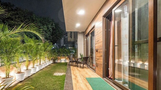 A modern building with a wooden deck, potted plants, and a seating area. - TIM Sector 51, ARTEMIS HOSPITAL 1 min walk, FORTIS & MEDANTA 4 mins drive (Gurugram)