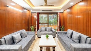 A modern room with two grey sofas, a white coffee table, and a ceiling fan. - TIM Sector 51, ARTEMIS HOSPITAL 1 min walk, FORTIS & MEDANTA 4 mins drive (Gurugram)