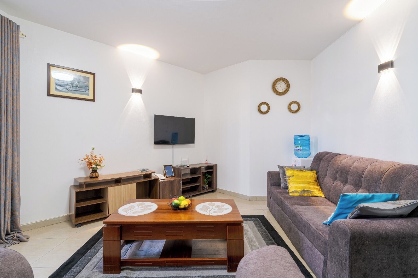 Een woonkamer met een bank, salontafel, televisie en een aan de muur bevestigde televisie.