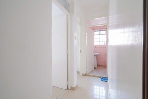 Un couloir menant à une salle de bain équipée de toilettes et d’un lavabo.