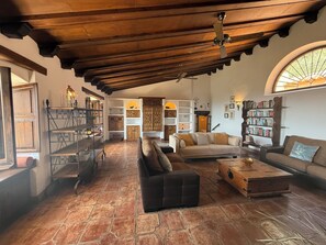 Cozy living area with a high ceiling, comfortable sofa, armchair, and fireplace.
