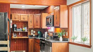 A compact kitchen with wooden cabinets, a built-in microwave, and a dishwasher. - Lake Access + Pools + Sports Complex | Near Skiing & Hiking | Foxden (East Stroudsburg)