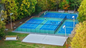 An outdoor tennis court surrounded by trees. - Lake Access + Pools + Sports Complex | Near Skiing & Hiking | Foxden (East Stroudsburg)