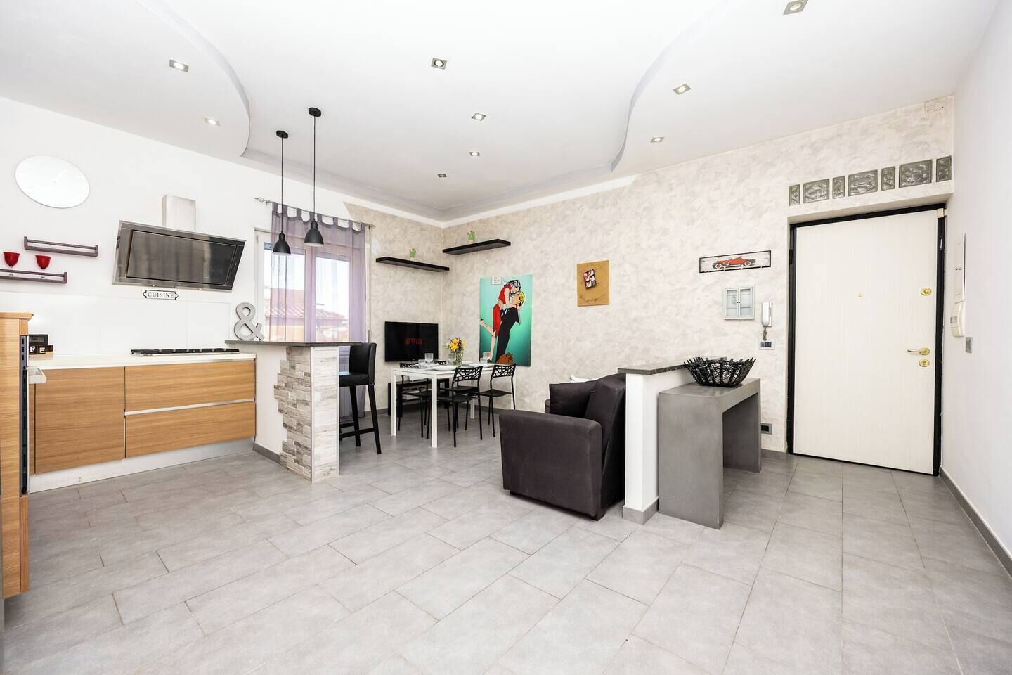 Una cocina moderna con comedor, televisor y una puerta con un adhesivo de coche.