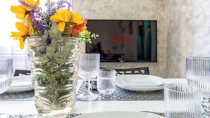 Ett matbord dukat med genomskinliga glas och en vas med gula blommor.