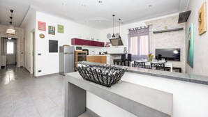Ett modernt kök med en central köksö, inbyggda vitvaror och en matplats med tv.