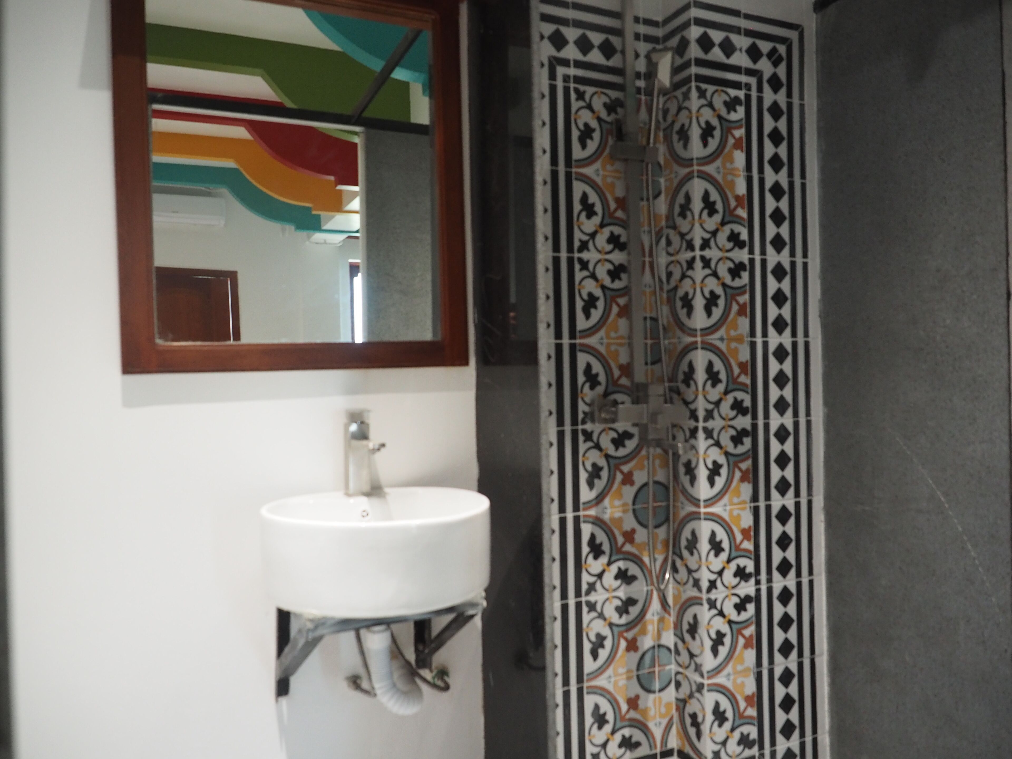 A bathroom with a white sink, a mirror, and a tiled shower enclosure.