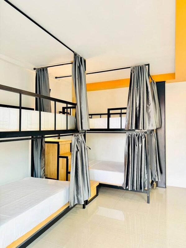 A dormitory-style room with bunk beds, a wooden desk, and a small cabinet. - Activate C3 Hostel (Phnom Penh)