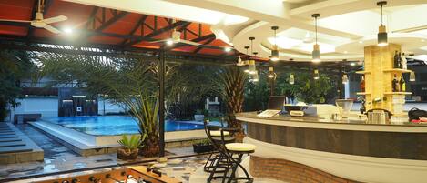 A pool area with a foosball table, a bar with a wooden counter, and a seating area with chairs and stools.