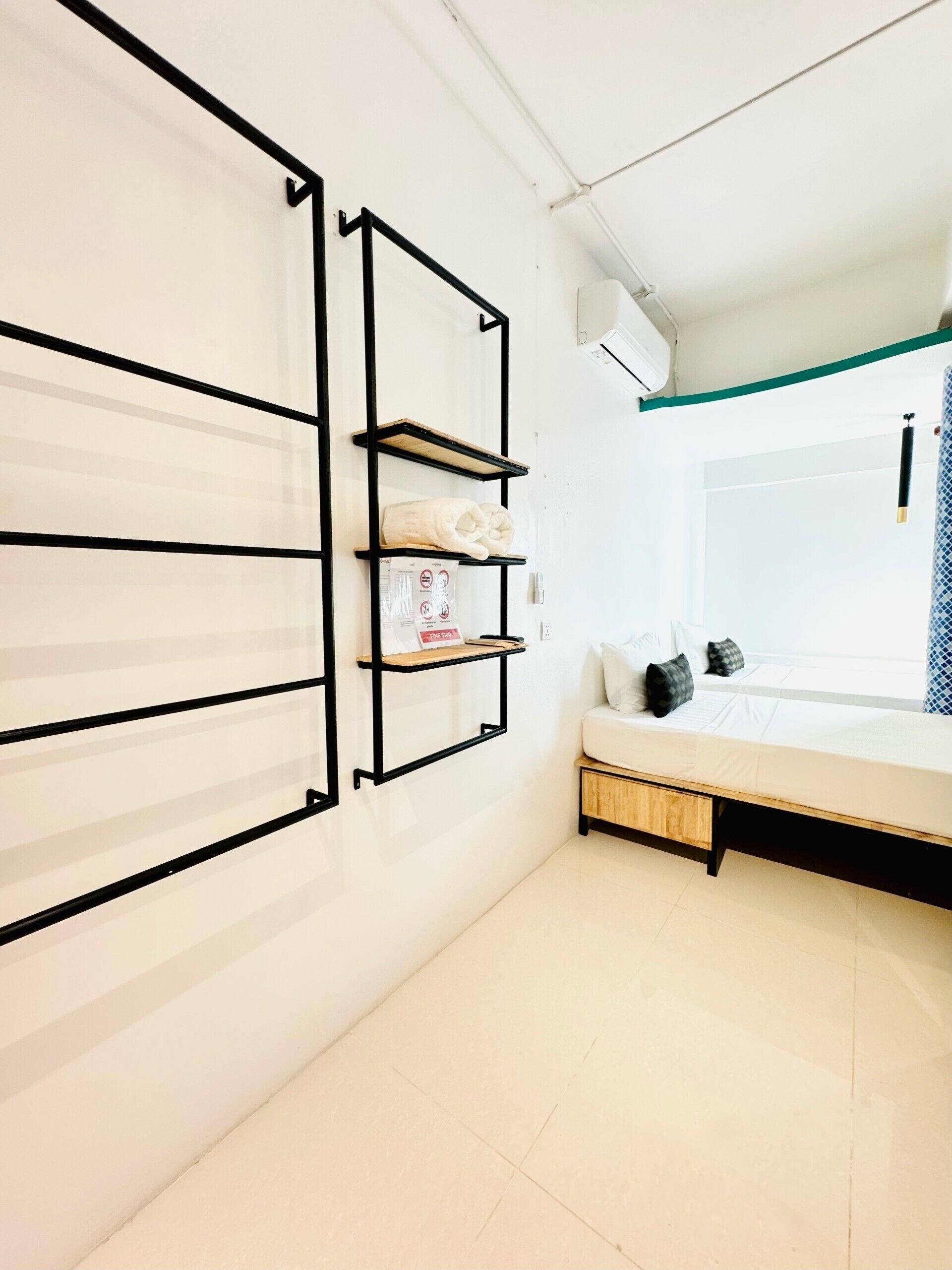 Un dormitorio con una cama, una estantería en la pared y una ventana con cortina.