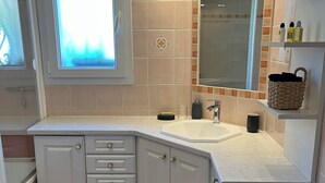 A bathroom with a white vanity, a large mirror, a window, and a patterned floor.