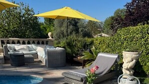 An outdoor dining area with a table set for breakfast, including croissants, eggs, and fruit.
