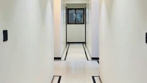 Un pasillo moderno con piso de color claro, líneas blancas y negras a rayas y una lámpara empotrada en el techo.