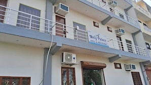 Un edificio de varios pisos con balcones, unidades de aire acondicionado y un letrero que dice Brij Palace Hotel & Restaurant.