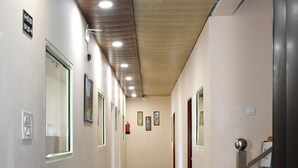 Un pasillo largo y estrecho con piso pulido, techo de madera y varias puertas y ventanas.
