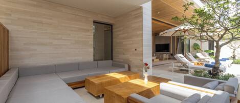 A modern living area with a sectional sofa, wooden coffee tables, and a ceiling fan.