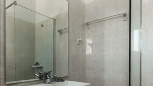 A modern bathroom with a white sink, a large mirror, and a glass shower enclosure.
