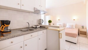 A modern kitchen with white cabinets, a granite countertop, a coffee maker, and a kettle.
