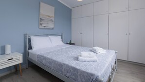 Un dormitorio con cama, mesita de noche, armario y una lámpara colgante.