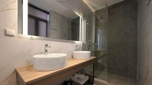 Une salle de bain moderne avec deux lavabos, un grand miroir et une douche à parois de verre.