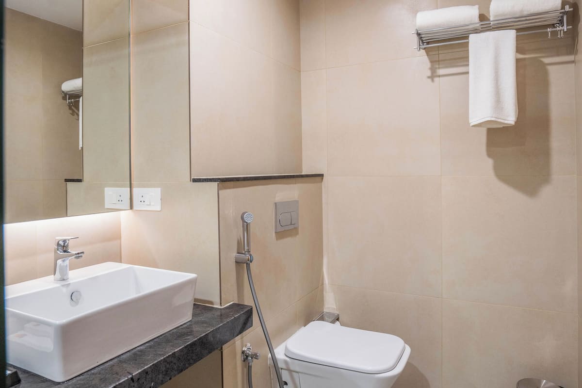 Un baño moderno con lavamanos, espejo, inodoro y toallero.
