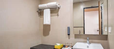 A bathroom with a marble countertop, a white sink, a towel rack with a rolled towel, a mirror, and a small box of toiletries.