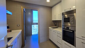 A modern kitchen with stainless steel appliances, a built-in oven, and a window overlooking a cityscape. - INTEMPO (2 BEDROOMS) (Benidorm)