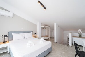 Ein modernes Hotelzimmer mit einem großen Bett, Nachttischen, einem Schreibtisch und einem Sessel.
